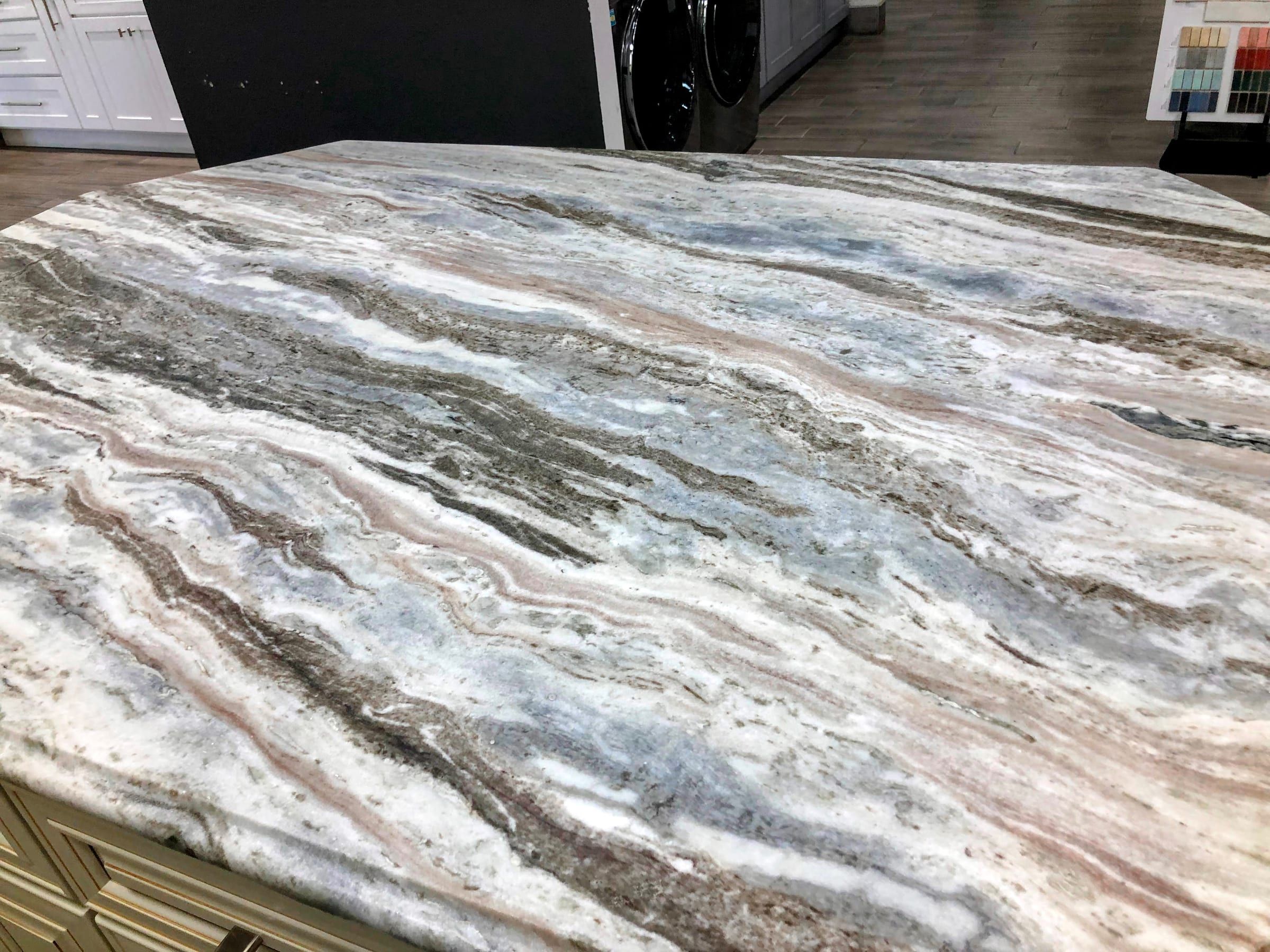 Close-up of a polished Fantasy Brown marble countertop showing flowing grey, white, and burgundy veining.