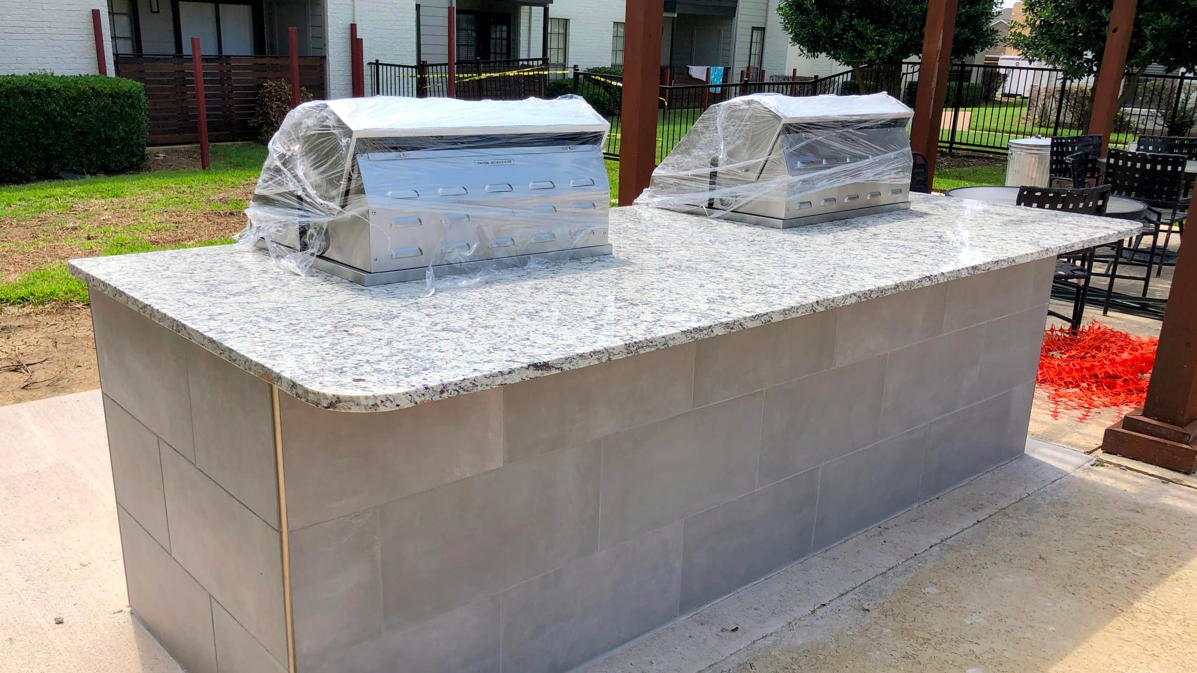 A speckled white and grey granite countertop installed on an outdoor kitchen island with two stainless steel grills.