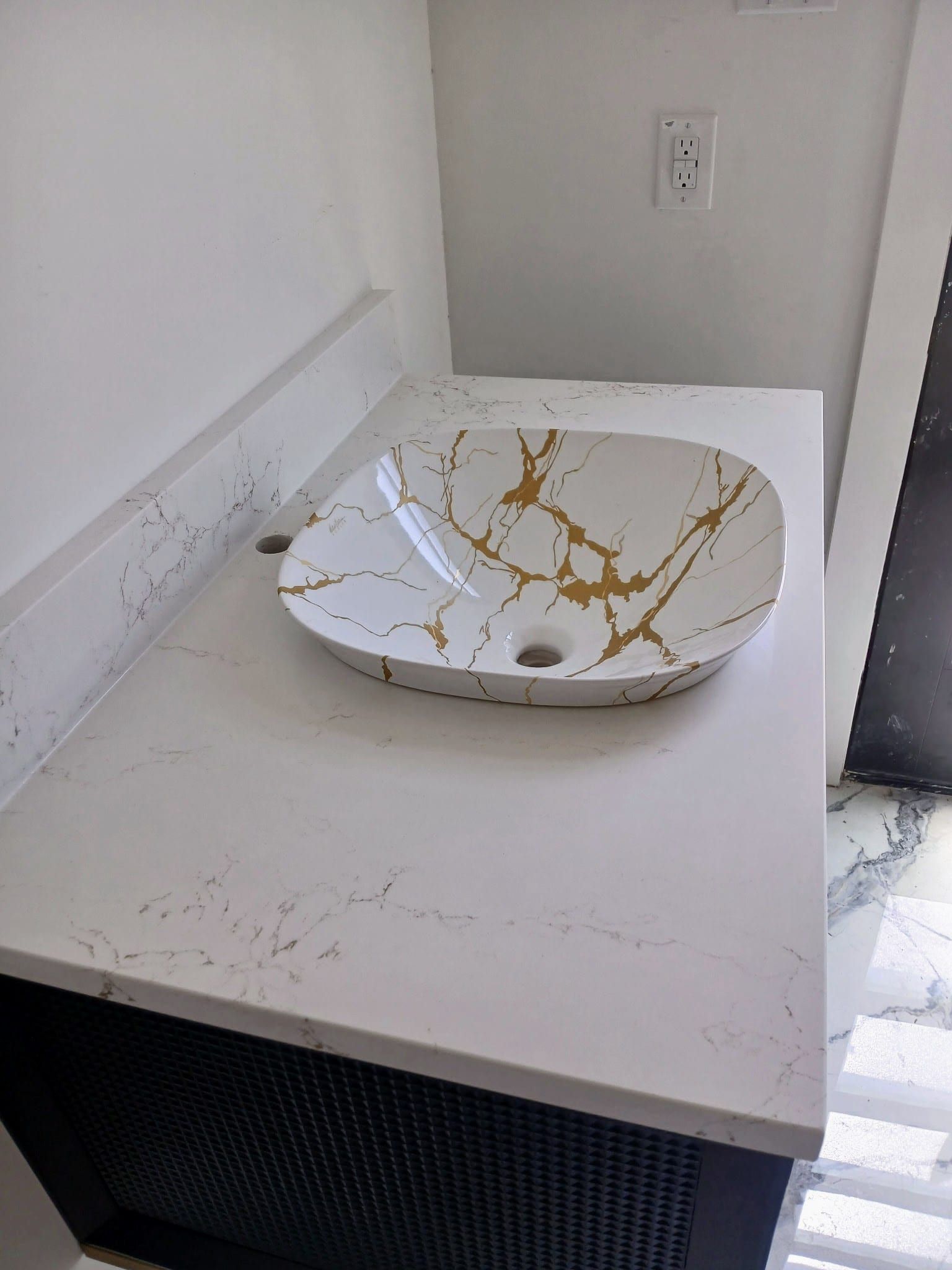 White quartz bathroom vanity with delicate grey veining and a matching gold-accented vessel sink.