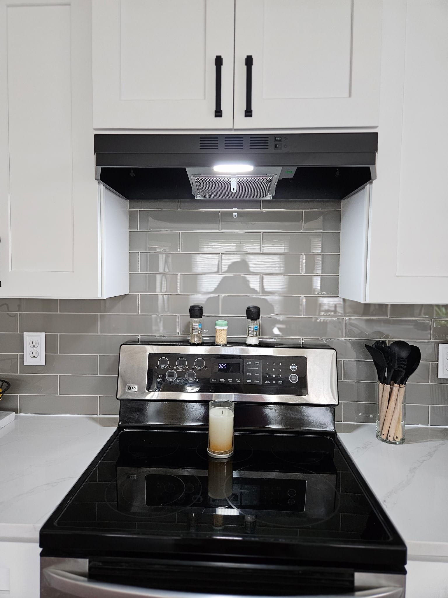 White quartz countertop with subtle grey veining paired with a glossy grey subway tile backsplash in a modern kitchen.