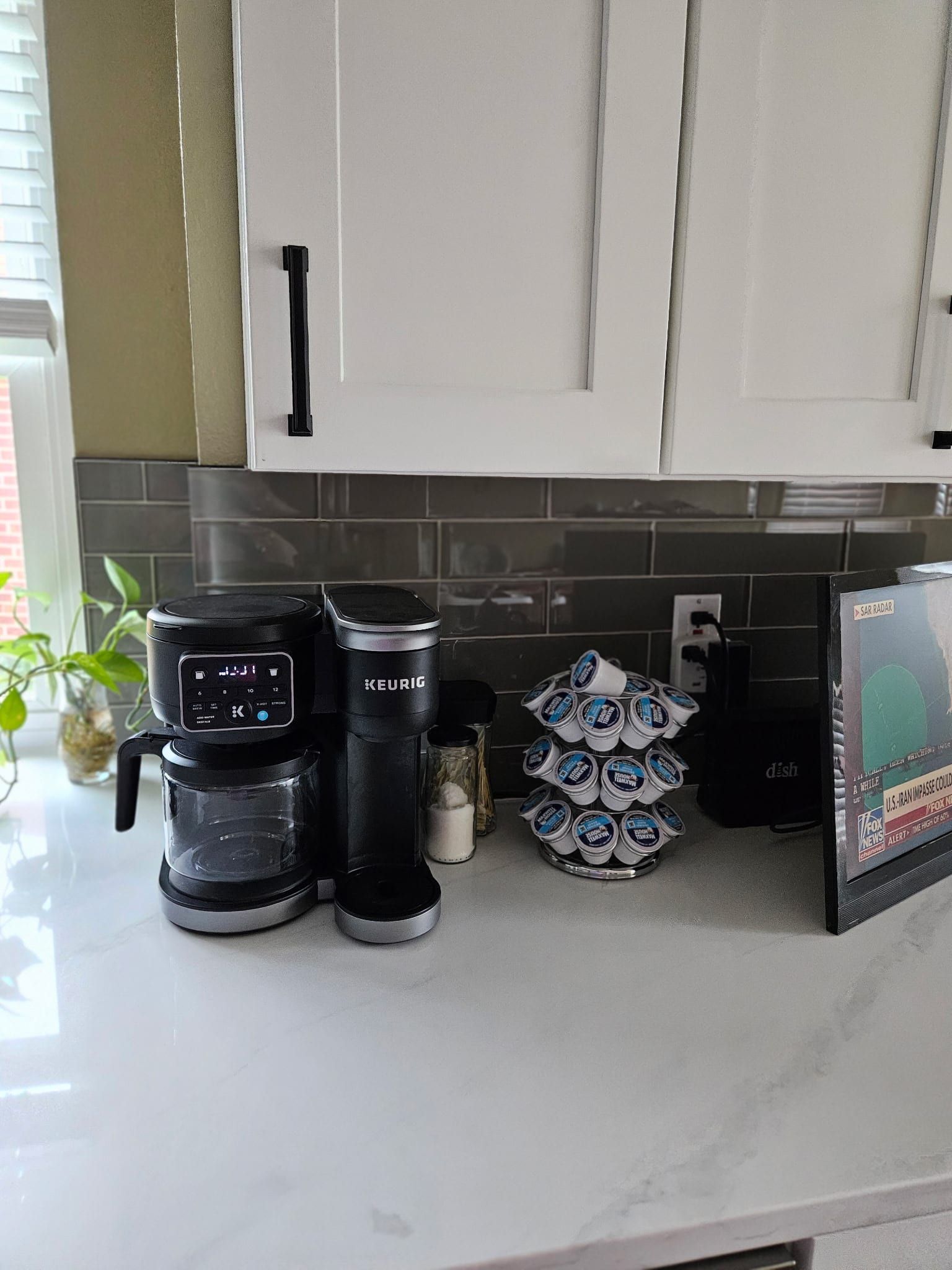 White quartz countertop with subtle grey veining in a kitchen featuring white cabinets and a grey subway tile backsplash.